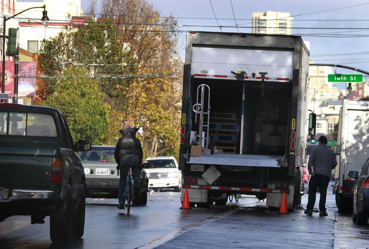 A bicyclist is forced to swerve into a traffic lane by a truck that double parked in the bike lane while making a delivery on Valencia Street near 16th Street in San Francisco, Calif. on Wednesday, Dec. 26 2012.