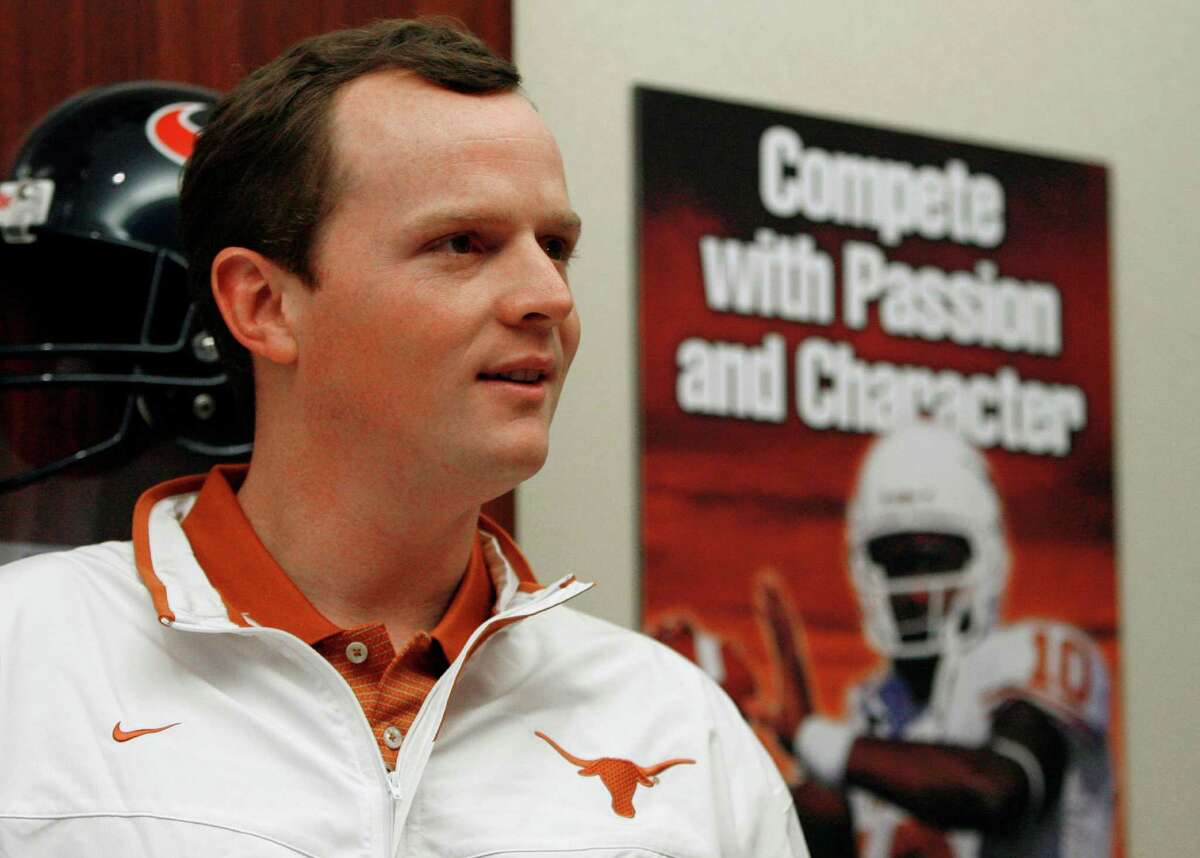 Major Applewhite stands near a poster featuring another former University of Texas quarterback as he waits to speak at a news conference Thursday, Jan. 17, 2008, in Austin, Texas. It was announced that Applewhite, who became a folk hero with his cherubic looks and cool demeanor on the field, has returned to be the Longhorns running backs coach and assistant head coach. (AP Photo/Harry Cabluck)