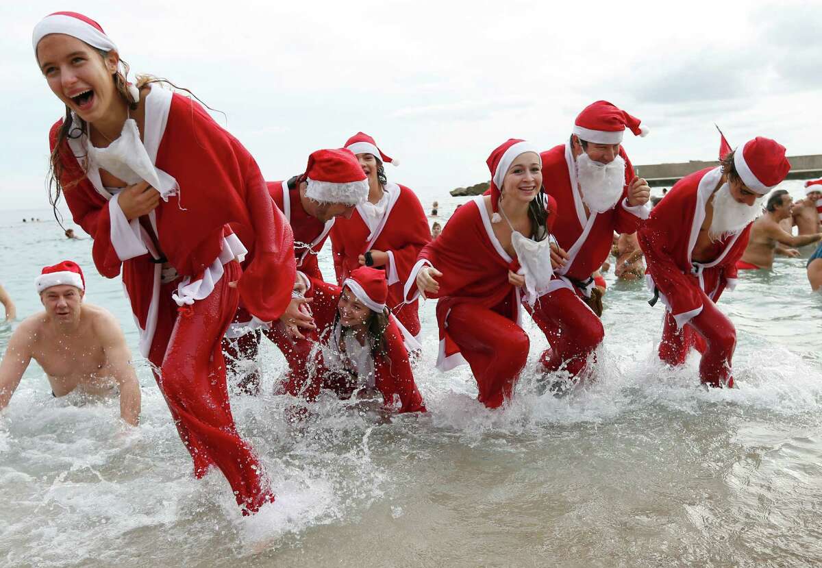 People dressed up as Santa Claus enjoy a traditional Christmas bath on December 23, 2012 in Monaco.