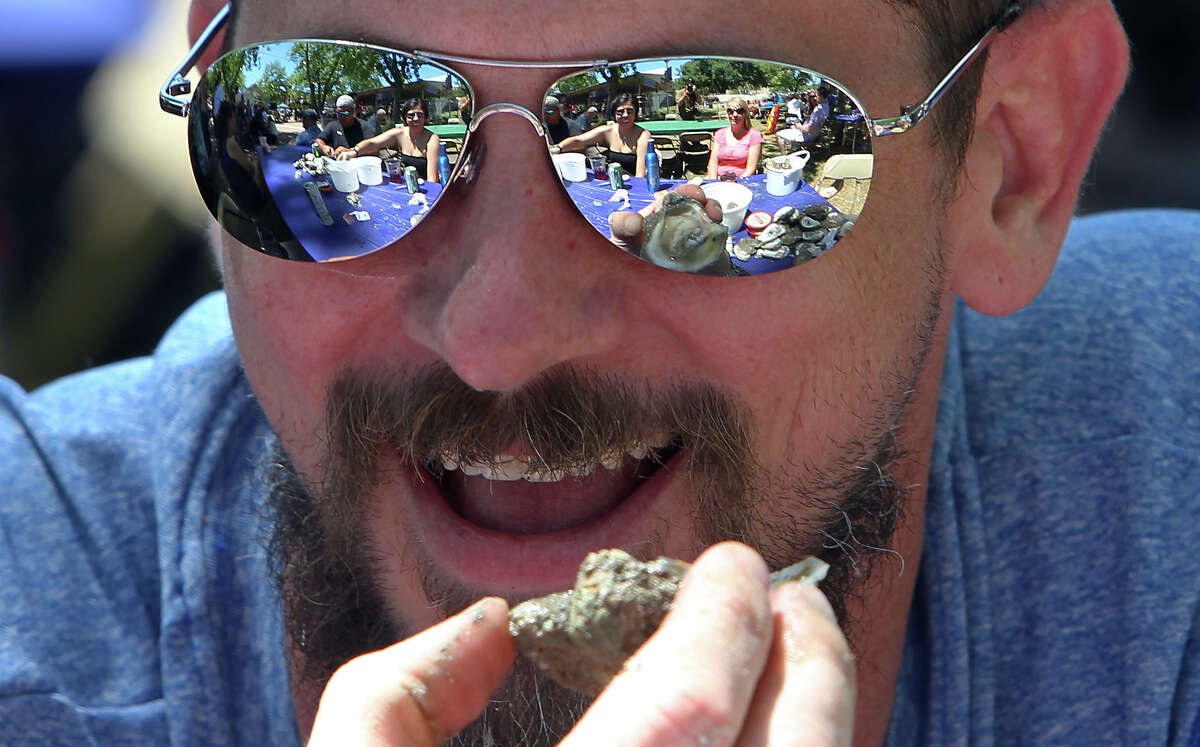 Ryan Wannemacher gets ready to devour a baked oyster as the scene of friends and shucked oysters reflect off his sunglasses at the 2012 Fiesta Oyster Bake at St. Mary's University on Saturday, Apr. 21, 2012. Proceeds from the event go toward scholarships and university programs.