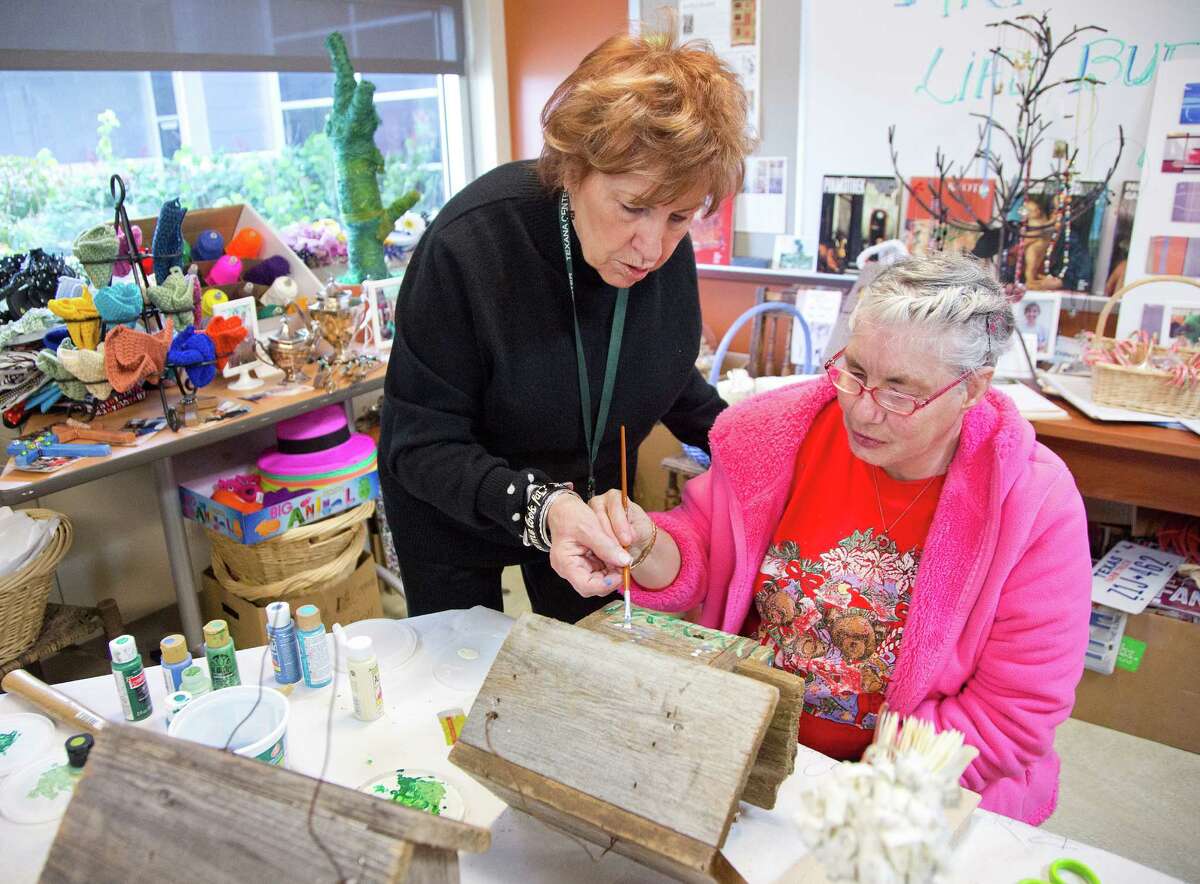 Volunteer Eileen McDowell, an artist who started the Texana Center art program 15 years ago and named it after her late daughter, helps Shirley Villareal paint.