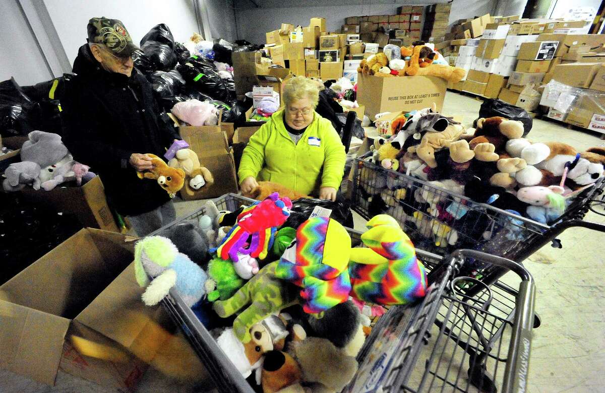 Volunteers, including Cheryl Ghent, center, sort donations in the "teddy bear room" of a Simms Lane warehouse in Newtown Thursday, Dec. 27, 2012.