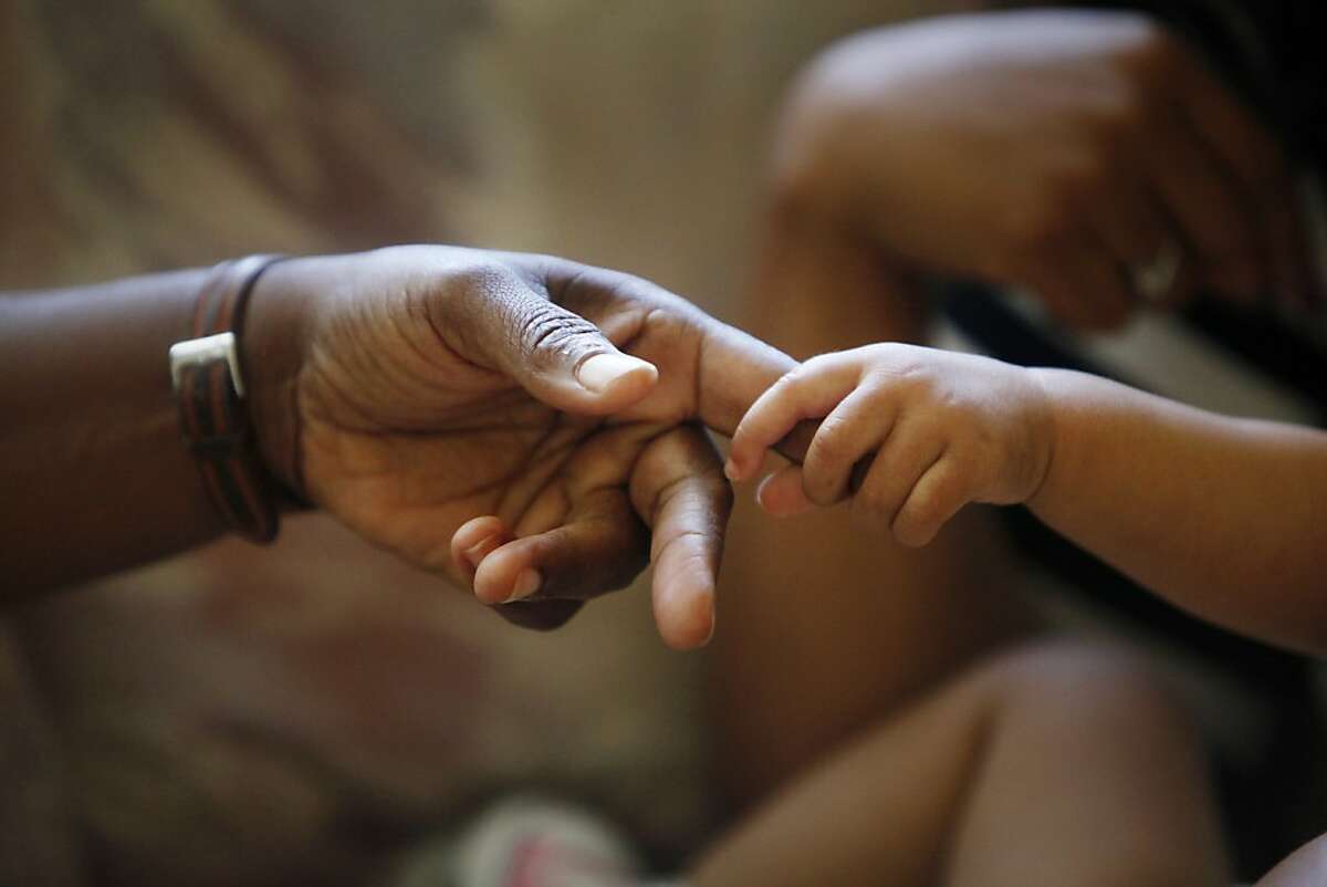 Sandra Tramiel (l to r), public health nurse, Improving Pregnancy Outcomes Program, and Vanessa Moore, 14 months, hold hands during a home appointment on Thursday, October 13, 2012 in Oakland, Calif.