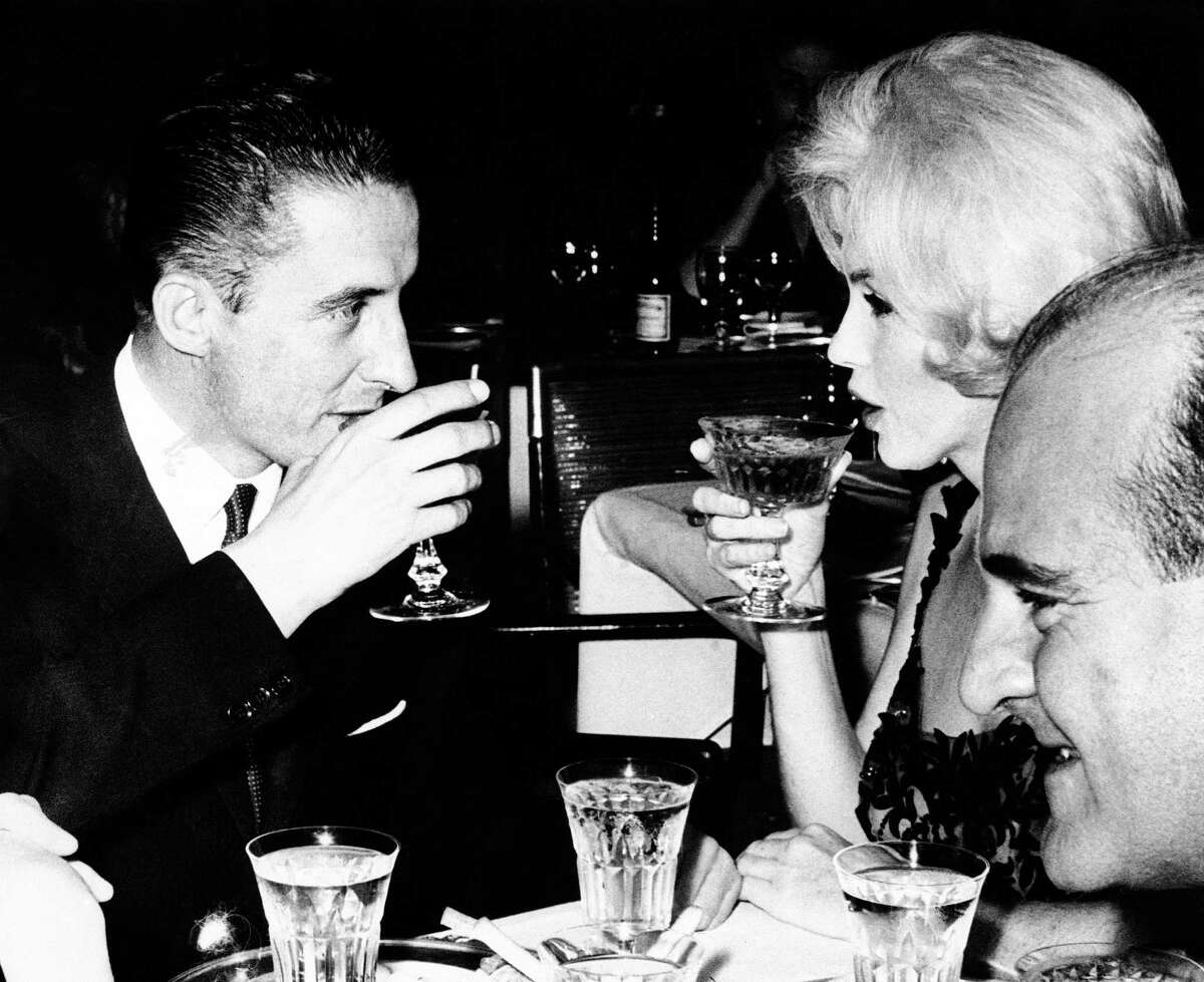 FILE - In this February 26, 1962 file photo, Marilyn Monroe and Jean Pierre Piquet, left, manager of Continental Hilton Hotel, are seen lifting their champagne glasses at a reception offered to the visiting star, in Mexico City. In late 2012, the FBI has released a new version of files it kept on Monroe that reveal the names of some of her acquaintances who had drawn concern from government officials and members of her entourage over their suspected ties to communism. (AP Photo, File)