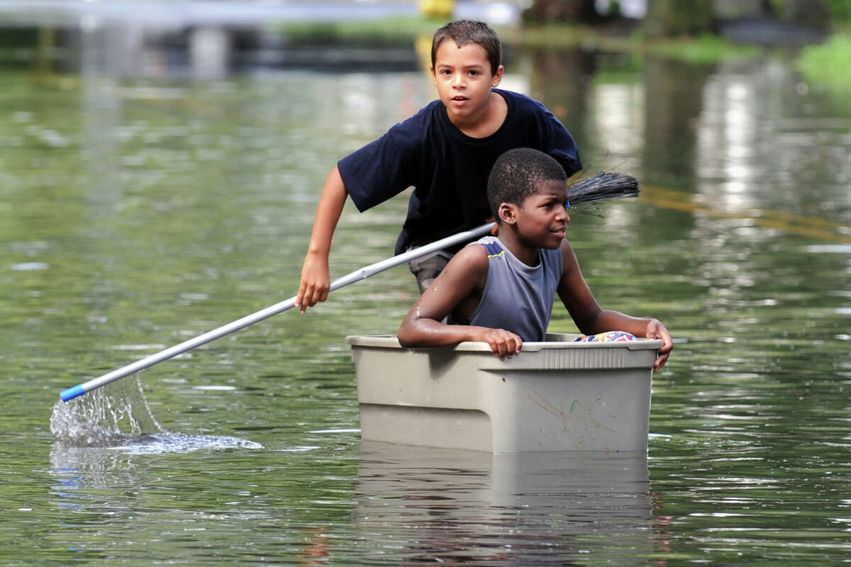 Iranistan Aveune, Bridgeport Nicolas Daniels, 9 (seated), and Joaquin Ortiz, 10, try to navigate the flood waters on Iranistan Ave., in Bridgeport, Conn. following Friday's storm, Aug. 10th, 2012.