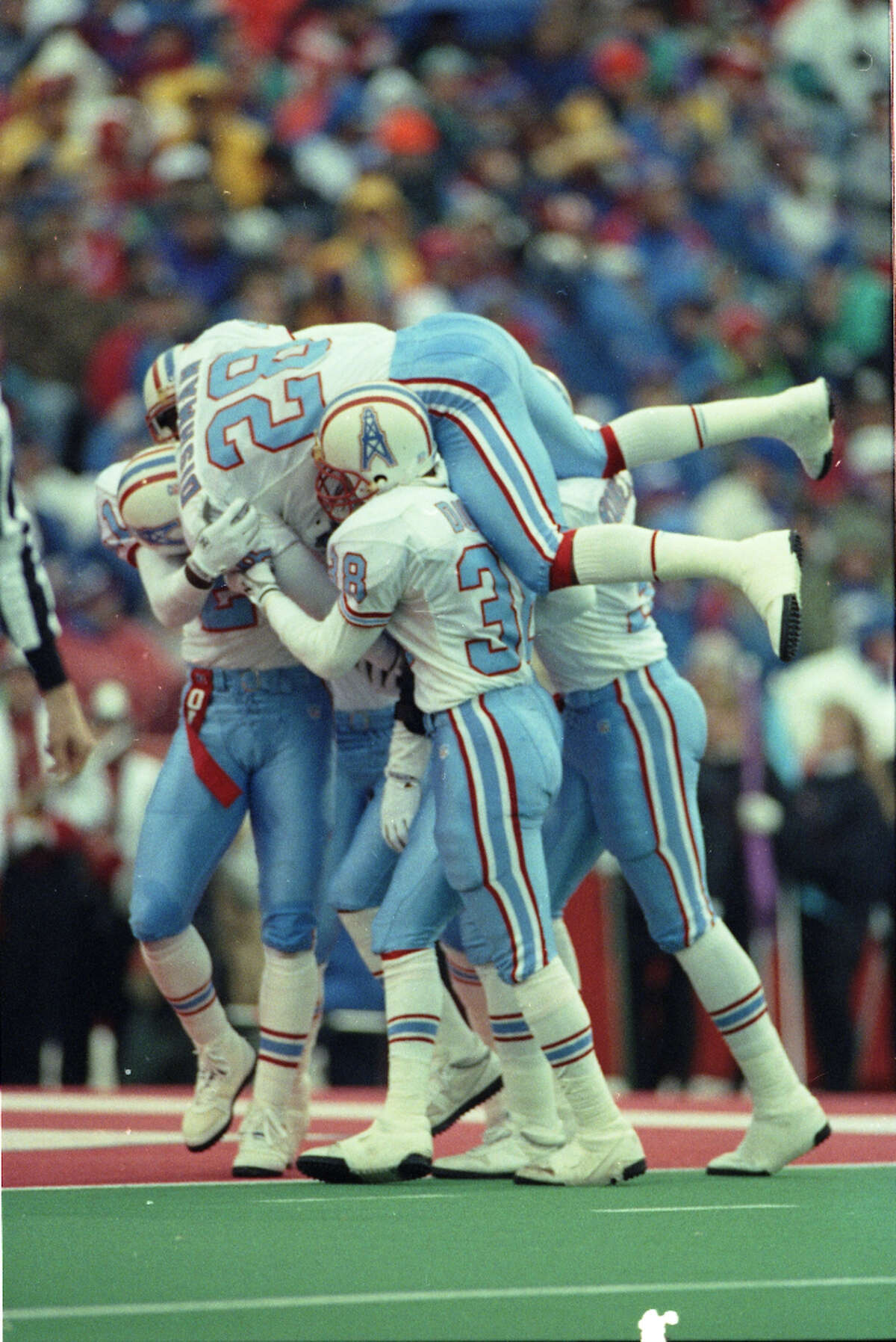 Oilers players mob Bubba McDowell after his third-quarter interception return for a touchdown in the AFC wildcard game against the Buffalo Bills.