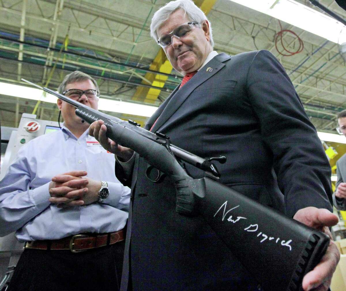 Then-presidential candidate Newt Gingrich holds a rifle at a Sturm Ruger firearms plant in New Hampshire last January. The conservative Republican signed the stock of the gun for the onlooking plant manager.