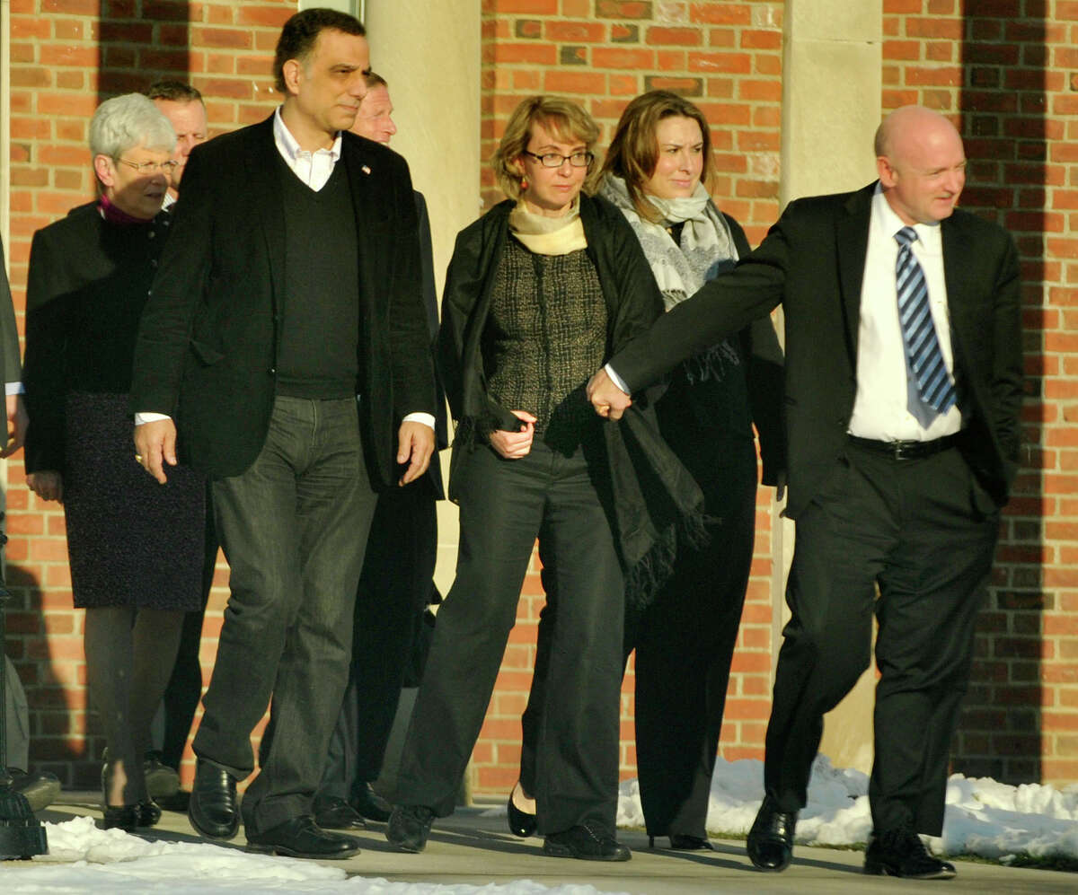Former Congresswoman Gabrielle Giffords, center, holds hands with her husband, Mark Kelly, while exiting Newtown Town Hall at Fairfield Hills Campus after meeting with Newtown First Selectman Pat Llodra and other officials on Friday, Jan. 4, 2013.