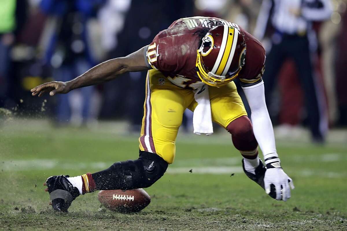 Washington Redskins quarterback Robert Griffin III twists his knees as he reaches for the loose ball after a low snap during the second half of an NFL wild card playoff football game against the Seattle Seahawks in Landover, Md., Sunday, Jan. 6, 2013. (AP Photo/Matt Slocum)