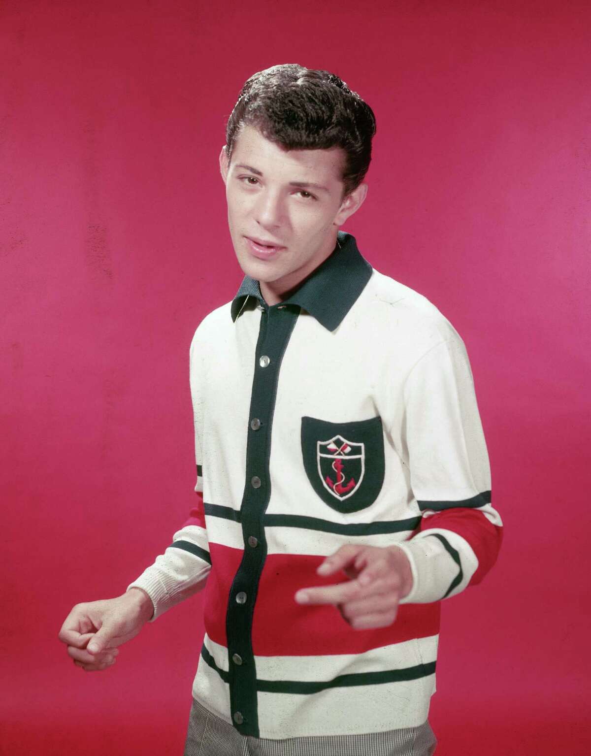 Then: American singer and actor Frankie Avalon wearing a red, white, and blue cardigan sweater in 1955.