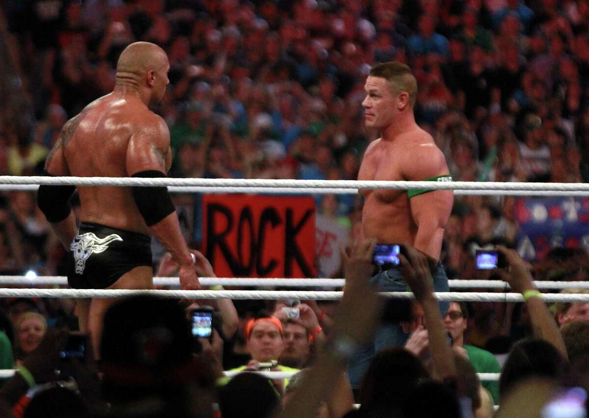 Dwyane "The Rock" Johnson, left, and John Cena face off in Miami at WrestleMania XXVIII in 2012. Both men will appear in Houston for WWE's 20th anniversary.