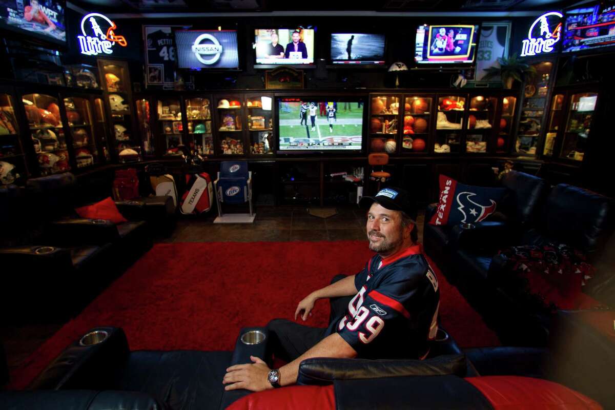Blake Barnes, a Texans fan, stands in his man cave that can seat about 50 people with multiple televisions, and cabinets full of sports memorabilia and other collectibles, Wednesday, Jan. 9, 2013, in Deer Park. ( Karen Warren / Houston Chronicle )