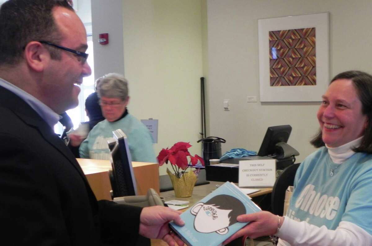 Bob Sussman, treasurer of the Fairfield Public Library Boards of Trustees and owner of Fairfield Center Jewelers, was one of the first Thursday to check out the book, "Wonder," from Anne Farkas of the circulation staff. FAIRFIELD CITIZEN, CT 1/10/13