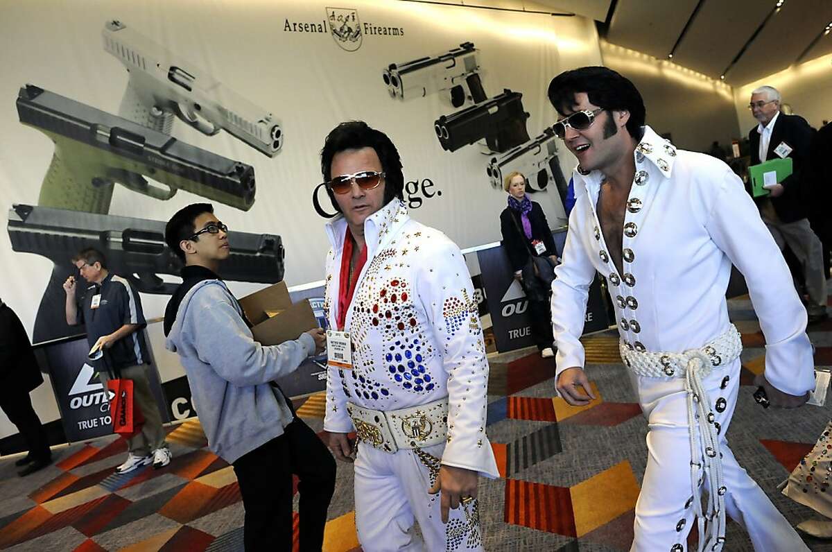 Elvis impersonators walk past a large banner for Arsenal Firearms in the lobby of the convention center. SHOT Show, the world's largest gun show, opened at the Sands Convention Center in Las Vegas, NV on Tuesday January 15th, 2013, where an estimated 60,000 industry enthusiasts are expected to attend.