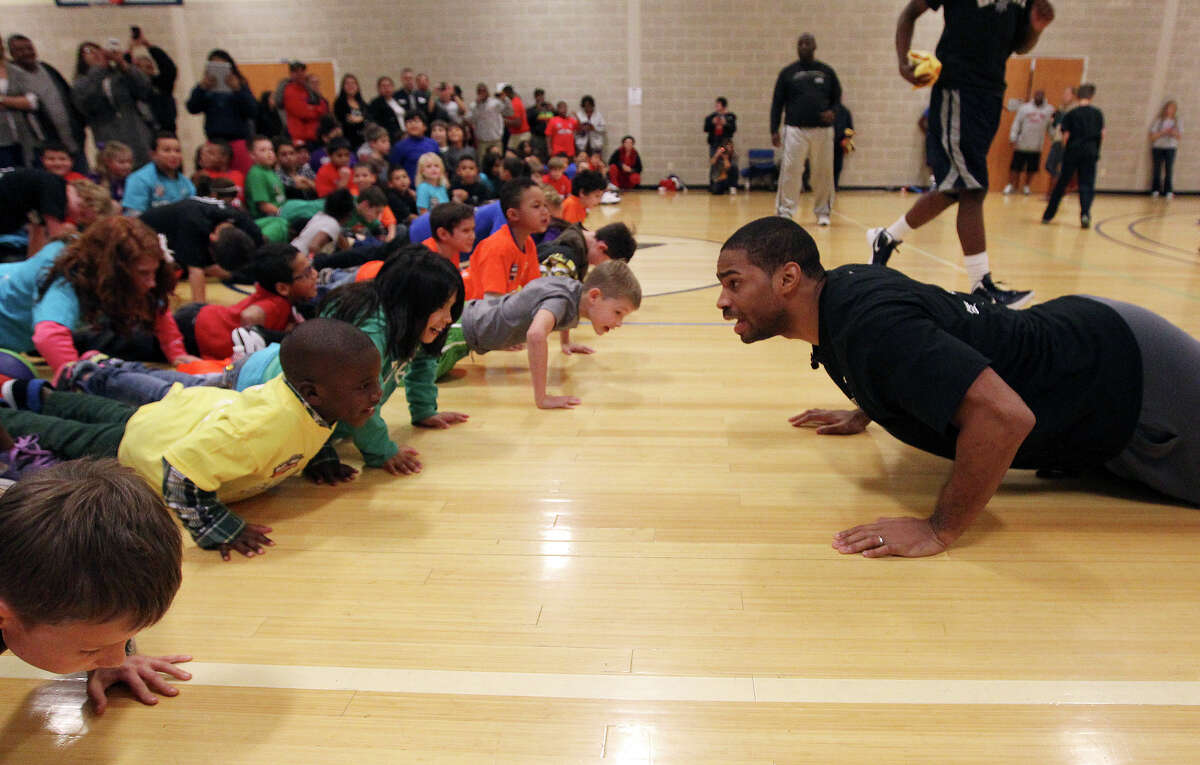 Spurs' guard Gary Neal (right) does push-ups with kids at the Spurs Youth Basketball League Kids Clinic at the Walzem YMCA on Tuesday, Jan. 15, 2013. 