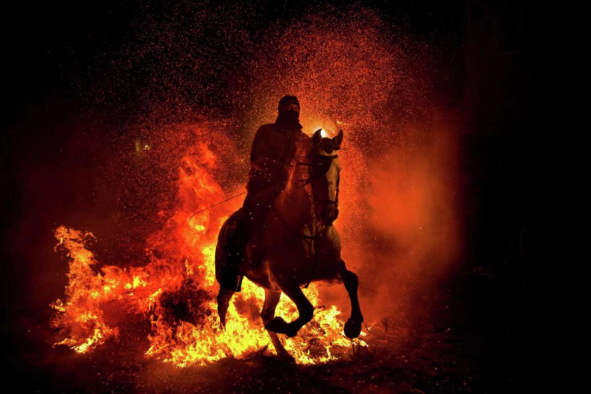 A man rides a horse through a bonfire in San Bartolome de Pinares, Spain, Wednesday, Jan. 16, 2013, in honor of Saint Anthony, the patron saint of animals. On the eve of Saint Anthony's Day, hundreds ride their horses trough the narrow cobblestone streets of the small village of San Bartolome during the 'Luminarias' a traditional festival that dates back 500 years and is meant to purify the animals with the smoke of the bonfires, and protect them for the year to come.