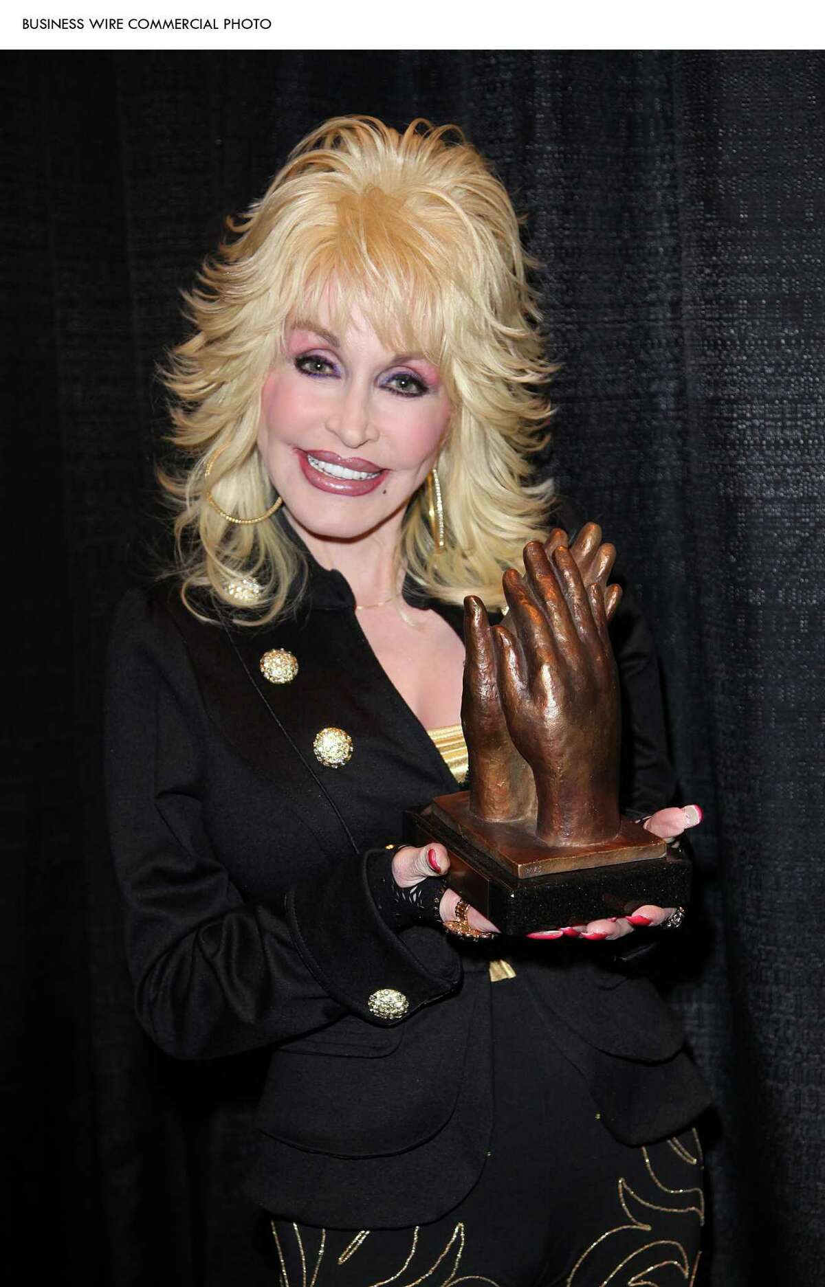 Dolly Parton poses with the prestigious Applause Award, presented to her Dollywood theme park at a special ceremony at the International Association of Amusement Parks & Attractions convention in Orlando, Fla., on Nov. 16. (Photo: Business Wire)