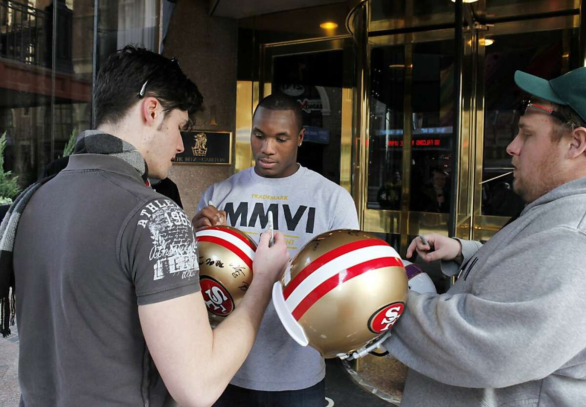 Darius Fleming of the 49ers signs helmets for autograph seekers (who declined to give their names) on Saturday at the 49ers team hotel in downtown Atlanta as stadium crews, players and fans prepare for the NFC Championship game in Atlanta, Ga., on Saturday, January 19, 2013.