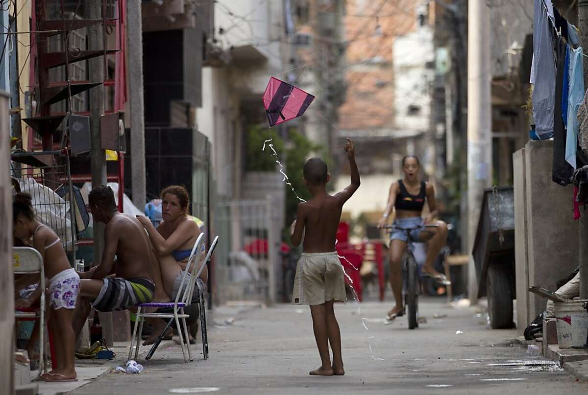 In this Dec. 28, 2012 photo, a child flies a kite in the Mare shantytown in Rio de Janeiro, Brazil. The city's densest neighborhoods, its favelas, or shantytowns blanket entire hillsides, providing most of the city's affordable housing. Now, those communities are being charted after decades of informality, each route and alley outlined and their names researched. A nonprofit organization run by current and former favela residents called Redes da Mare kick-started the first mapping program in the grouping of favelas known as Mare with a simple but powerful goal: putting their homes on the map, with named streets, zip codes and official addresses. (AP Photo/Silvia Izquierdo)