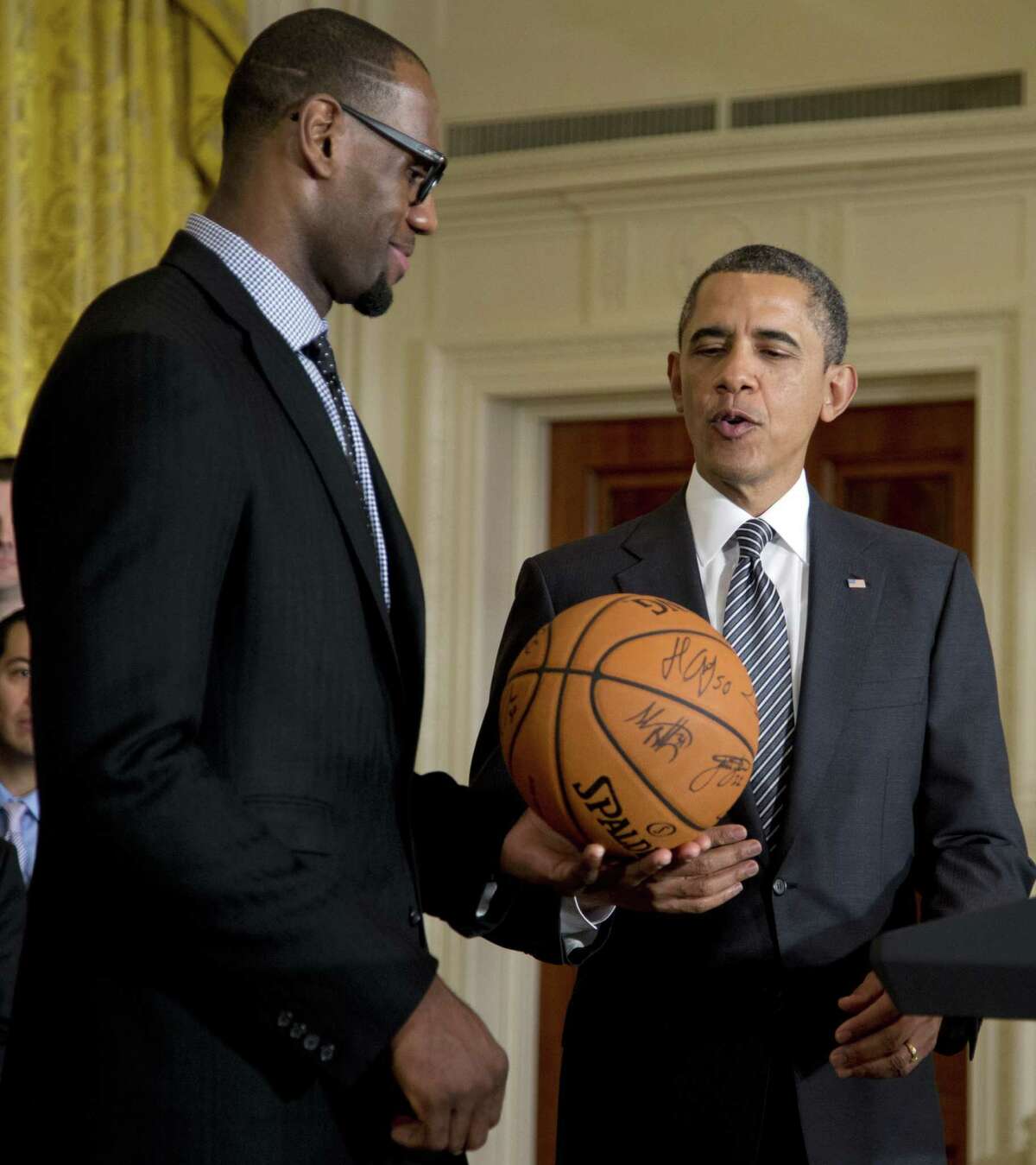 President Barack Obama accepts a signed basketball from Miami Heat forward LeBron James as he welcomes the the NBA basketball champion Miami Heat, to the East Room of the White House, Monday, Jan. 28, 2013, in Washington. (AP Photo/Carolyn Kaster)