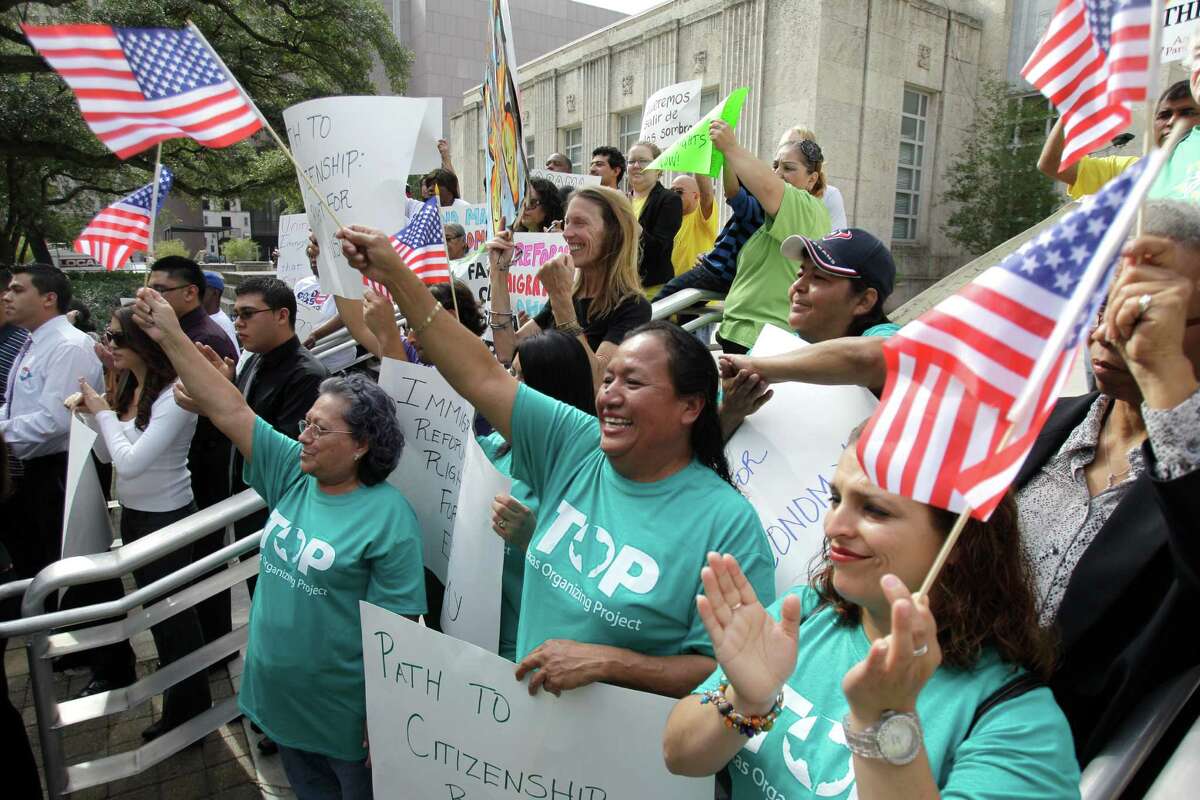 Members of the Texas Organizing Project Alicia Hernandez, center, and Karla Vargas, right, like what they hear as they join other local immigration reform advocates at an immigration reform news conference Monday at Houston City Hall.