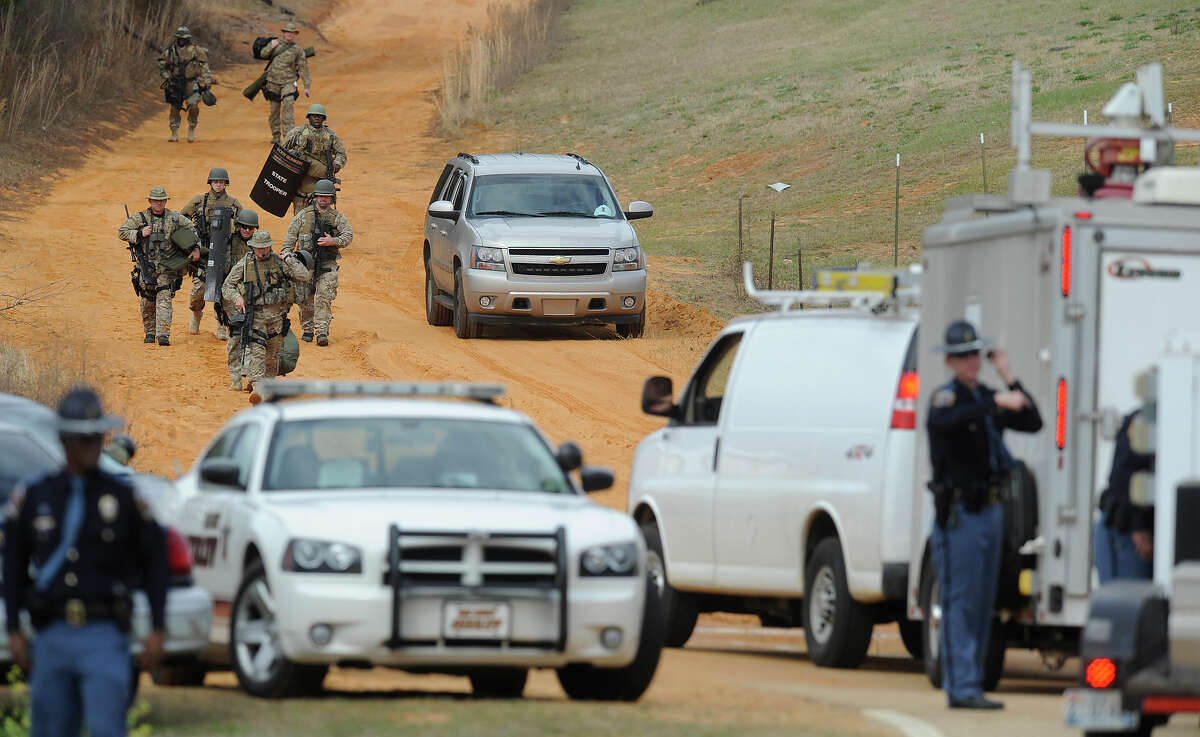 Heavily armed men move away from the suspects home at the scene of a Dale County hostage scene in Midland City, Ala. on Wednesday Jan. 30, 2013. Authorities were locked in a standoff Wednesday with a gunman authorities say on Tuesday intercepted a school bus, killed the driver, snatched a 6-year-old boy and retreated into a bunker at his home in Alabama.