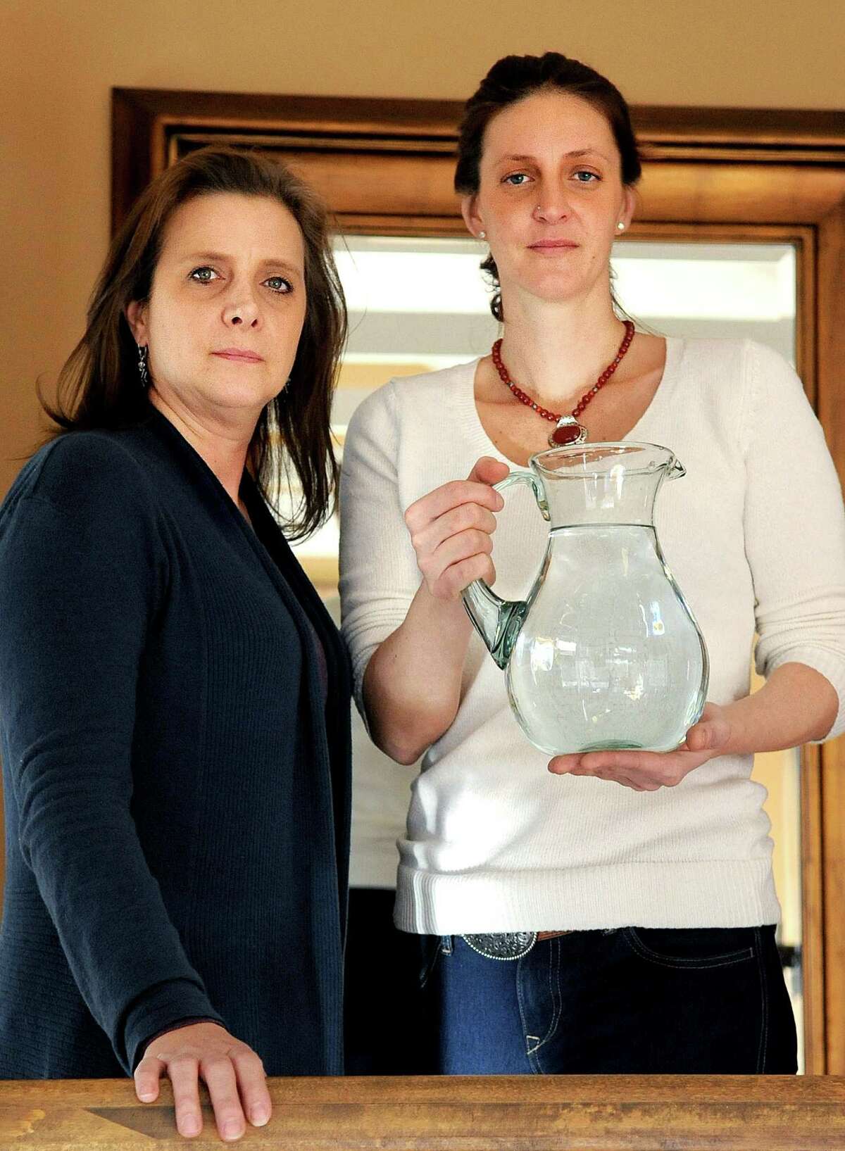 Jessica Penna holds a pitcher of water as she stands with her sister, Michelle Babyak, in Penna's Weston home on Thursday, January 31, 2013. Penna's home has well-water which is contaminated with arsenic which Penna believes has caused her health problems. Babyak, of Newtown, has radon in her well water.
