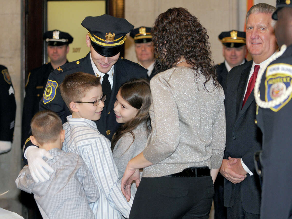 Commander Jeffrey Roberts gets hugs from his family (from left) Brady, 6, Max, 10, Shay, 9, and his wife Christine during a promotion ceremony at City Hall Friday Feb. 1, 2013 in Albany, N.Y. Mayor Jennings, right, and Chief Krokoff swore in nine newly promoted members of the Albany Police Department. (Lori Van Buren / Times Union)