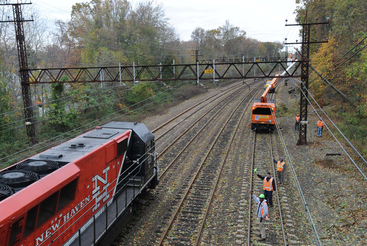 A New Haven Line Metro-North train heads north past a clean-up crew that was attempting to clear a downed tree that was resting on the electric lines by the railroad tracks near the West Street overpass in Mamaroneck, N.Y. during the aftermath of Hurricane Sandy. Metro-North is now planning to trim trees in Greenwich and Stamford that seeks to avoid a repeat of last August’s power outage, when a tree fell on a main transmission line, knocking out power to 99 percent of Greenwich.