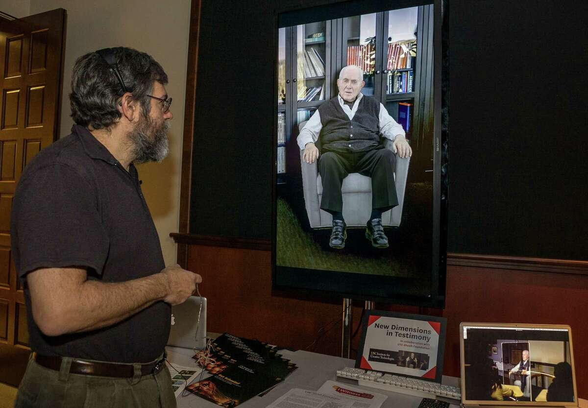 Computer scientist David Traum, with the University of Southern California Institute for Creative Technologies, interacts with Holocaust survivor Pinchas Gutter, seen on a "Virtual Survivor Visualization."