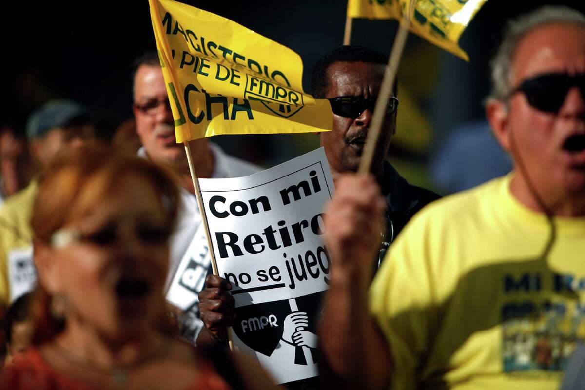 A retiree carries a sign that reads, in Spanish, "Do not play with my pension" during a protest outside the government pension headquarters last week in San Juan, Puerto Rico.