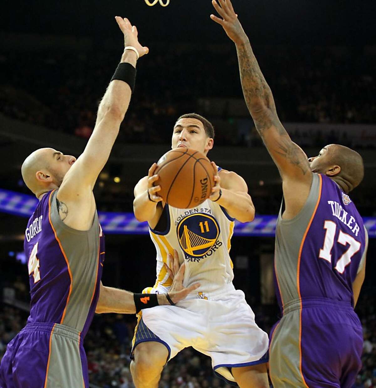 Golden State Warriors guard Klay Thompson (11) shoots between two Phoenix Suns defenders in the first half of their NBA basketball game Saturday, Feb. 2, 2013 at the Oakland Coliseum in Oakland California.