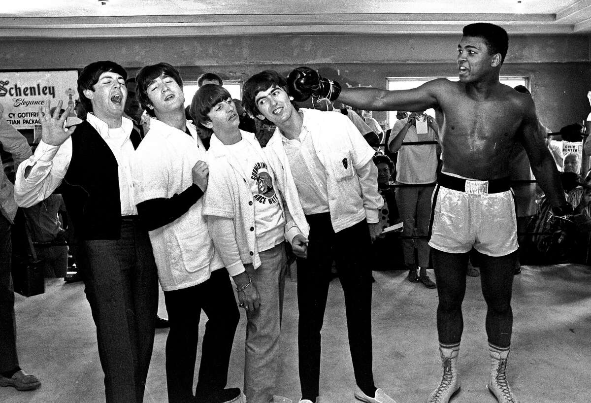 The Beatles, from left, Paul McCartney, John Lennon, Ringo Starr, and George Harrison, take a fake blow from Cassius Clay, who later changed his name to Muhammad Ali, while visiting the heavyweight contender at his training camp in Miami Beach, Fla.