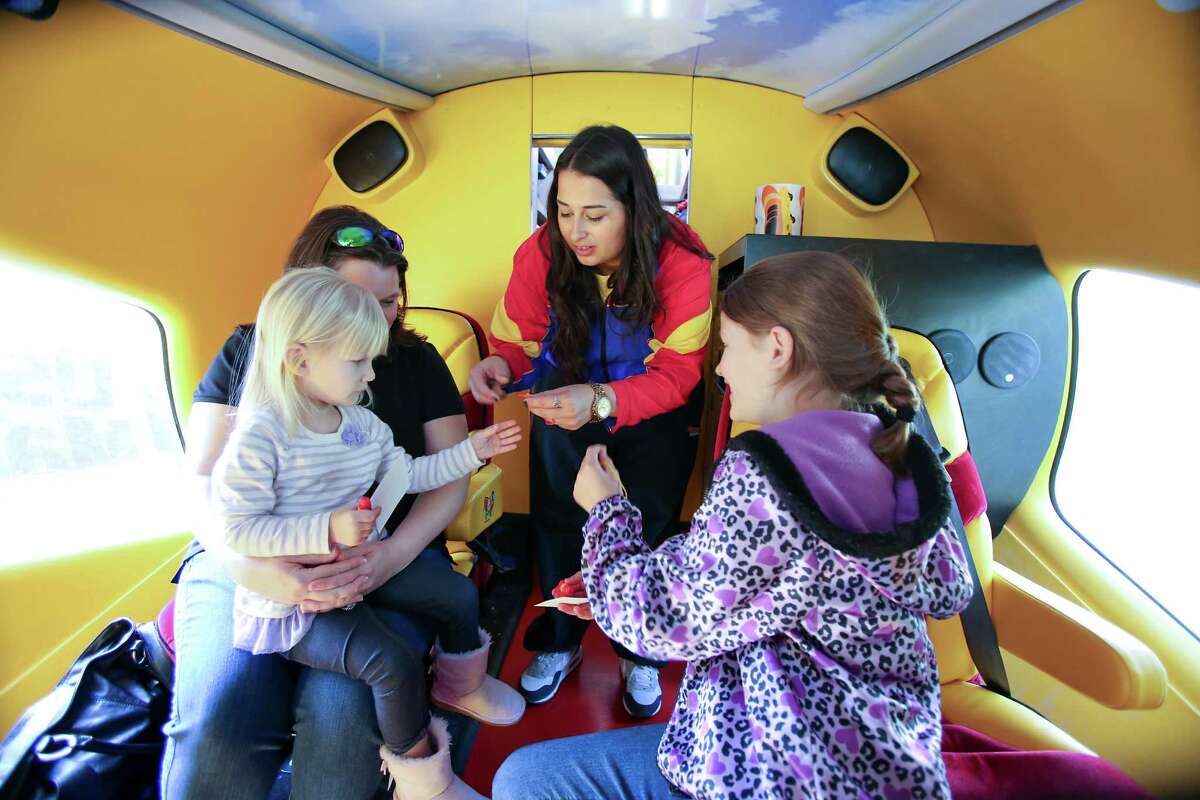 Emma Cuellar hands Oscar Mayer key chains, stickers and whistles to Robbie Durham and her daughters, Maggie, 3, and Kaitlynn, 10, inside the Wienermobile during a stop last week in Houston. The Durhams drove from Porter to see it.