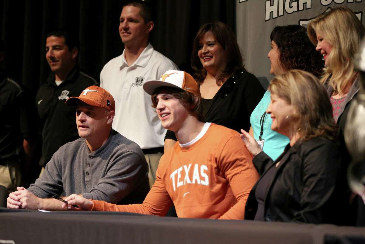 Steele High School football player Erik Huhn, front center, flanked by his father, Jeff Huhn and his mother, Sandy Huhn, smiles Wednesday Feb. 6, 2013 after signing a letter of intent on National Signing Day to play football at the University of Texas.