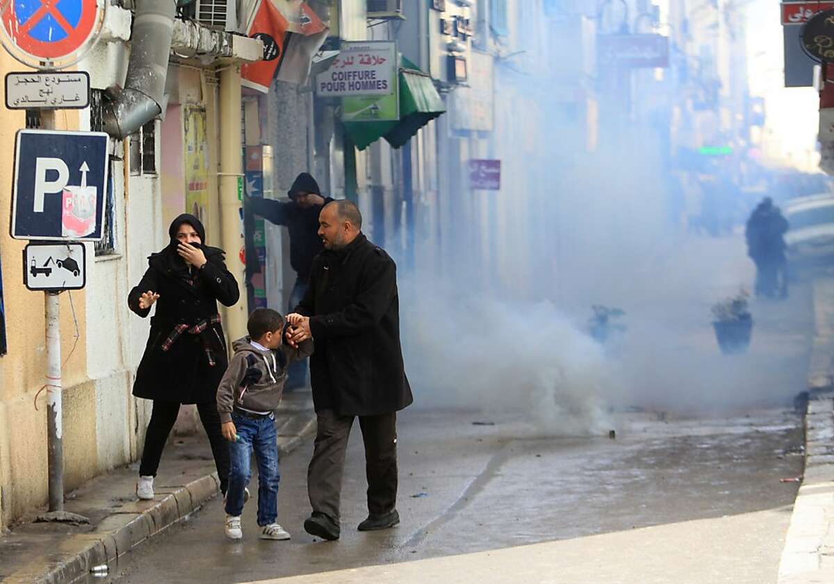 A family flees tear gas during a demonstration in Tunis, Thursday, Feb.7, 2013. The Islamist party dominating Tunisia's ruling coalition on Thursday rejected its own prime minister's decision to form a non-partisan technocratic government to try to appease critics, signaling that the political crisis brought on by the assassination of a prominent leftist politician is far from over. (AP Photo)