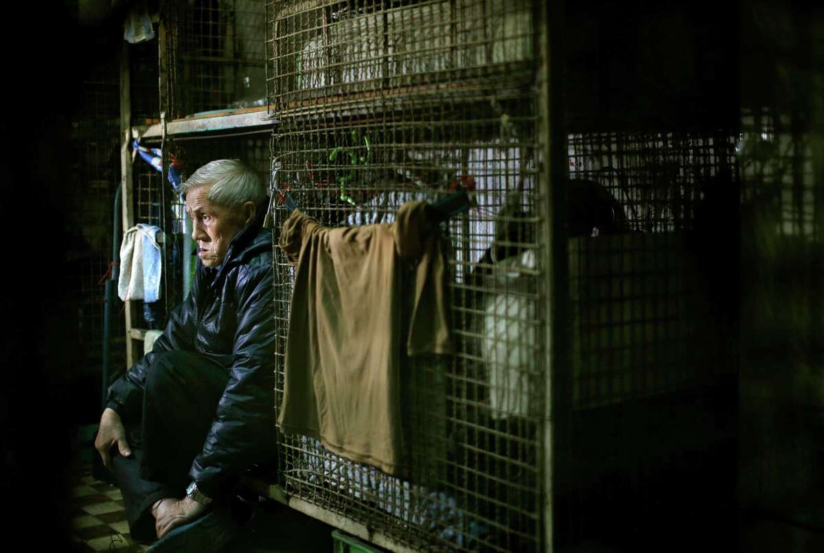In this Jan. 25, 2013 photo, 77-year-old Yeung Ying Biu sits inside his 1.5 square meter (16 square feet) cage, which he calls home, in Hong Kong. For many of the richest people in Hong Kong, one of Asia's wealthiest cities, home is a mansion with an expansive view from the heights of Victoria Peak. For some of the poorest, home is a metal cage. Some 100,000 people in the former British colony live in what's known as inadequate housing, according to the Society for Community Organization, a social welfare group. (AP Photo/Vincent Yu)