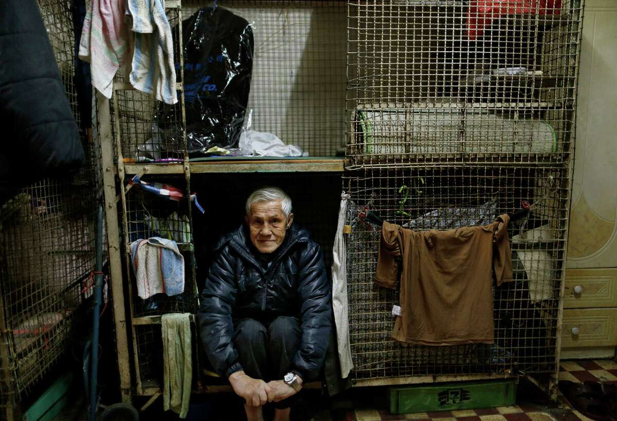 In this Jan. 25, 2013 photo, 77-year-old Yeung Ying Biu sits partially inside the cage, measuring 1.5 square meters (16 square feet), which he calls home, in Hong Kong. For many of the richest people in Hong Kong, one of Asia's wealthiest cities, home is a mansion with an expansive view from the heights of Victoria Peak. For some of the poorest, home is a metal cage. Some 100,000 people in the former British colony live in what's known as inadequate housing, according to the Society for Community Organization, a social welfare group. (AP Photo/Vincent Yu)