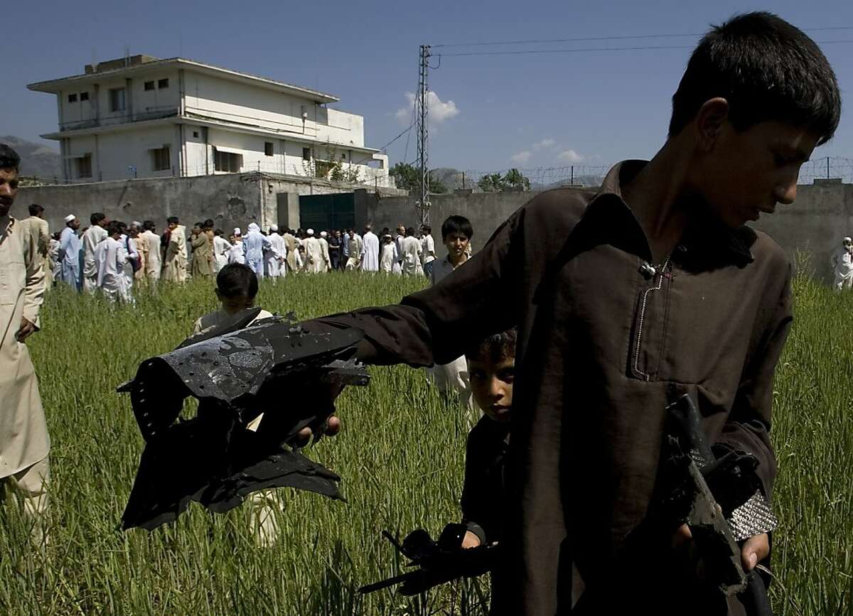 A Pakistani youngster shows metal pieces collected from wheat field outside a house, seen background, where al-Qaida leader Osama bin Laden lived in Abbottabad, Pakistan, on Tuesday, May 3, 2011. Local residents showed off small parts of what appeared tobe a U.S. helicopter that Washington said malfunctioned and was disabled by the American commando strike team as they retreated, while Pakistan's leader on Tuesday denied suggestions that his country's security forces had sheltered Osama bin Laden.