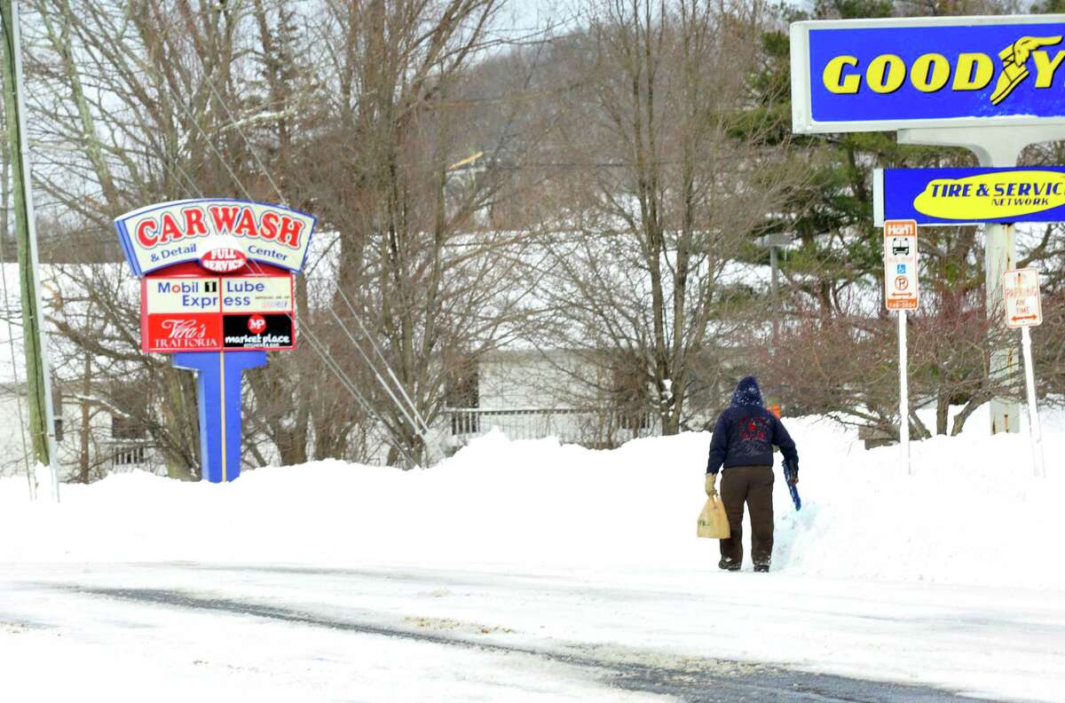 A lone pedestrian with a snow shovel walks along Mill Plain in Danbury Saturday, Feb. 9, 2013.