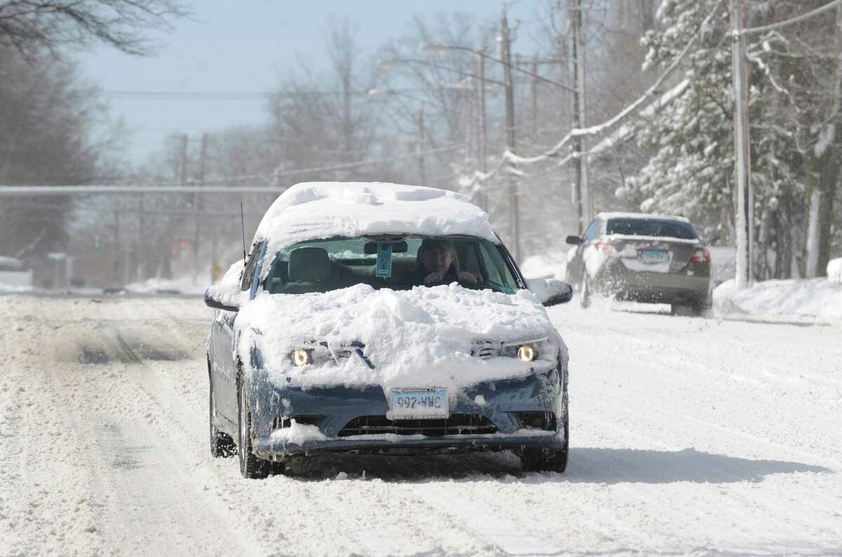 A snow-covered car travels on West Putnam Avenue during the aftermath of the blizzard that hit Greenwich, Conn., Saturday morning, Feb. 9, 2013.