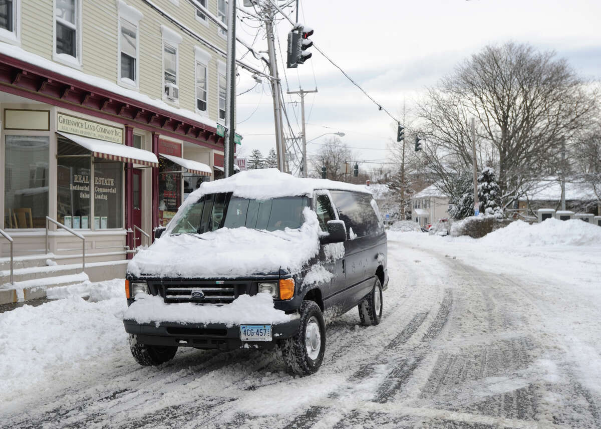 A vehicle covered with snow heads through downtown Byram during the aftermath of the blizzard that hit Greenwich, Conn., Saturday morning, Feb. 9, 2013.
