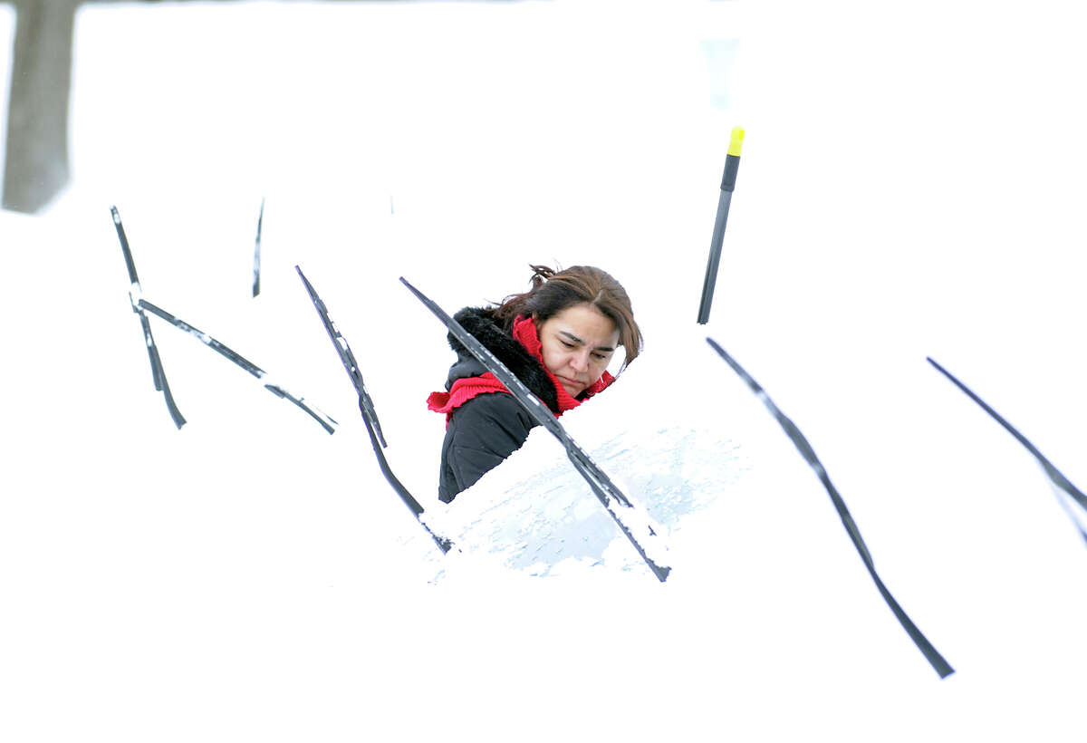 A woman clears her car of snow during the aftermath of the blizzard at the Armstrong Court Public Housing Complex, Greenwich, Conn., Saturday morning, Feb. 9, 2013.
