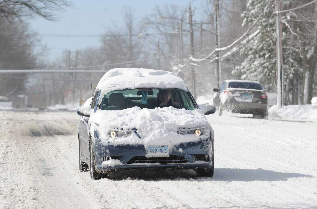 A snow-covered car travels on West Putnam Avenue during the aftermath of the blizzard that hit Greenwich, Conn., Saturday morning, Feb. 9, 2013.