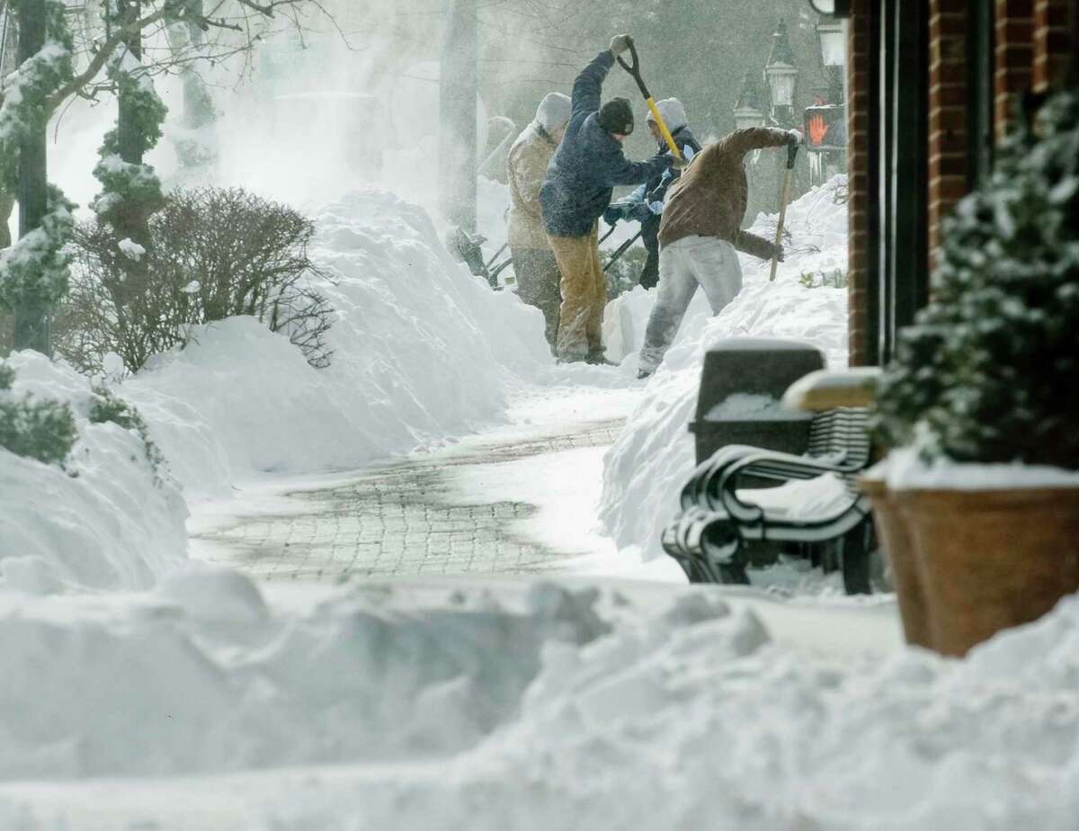 Workers shovel a sidewalk frantically in blowing snow on Main Street in Ridgefield after the snowstorm. Saturday, Feb. 9, 2013