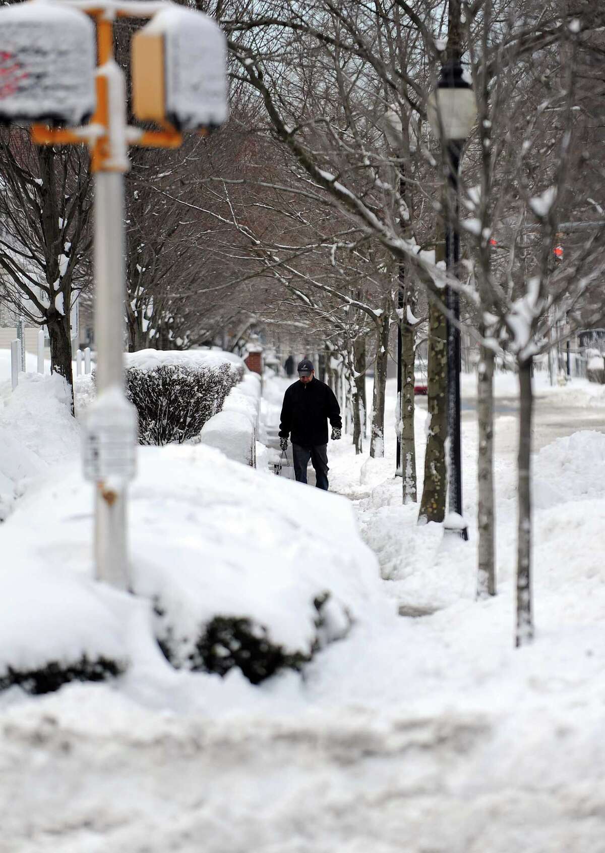 A pedestrian walks down a snowy sidwalk in Stamford, Conn., on Saturday, February 9, 2013.