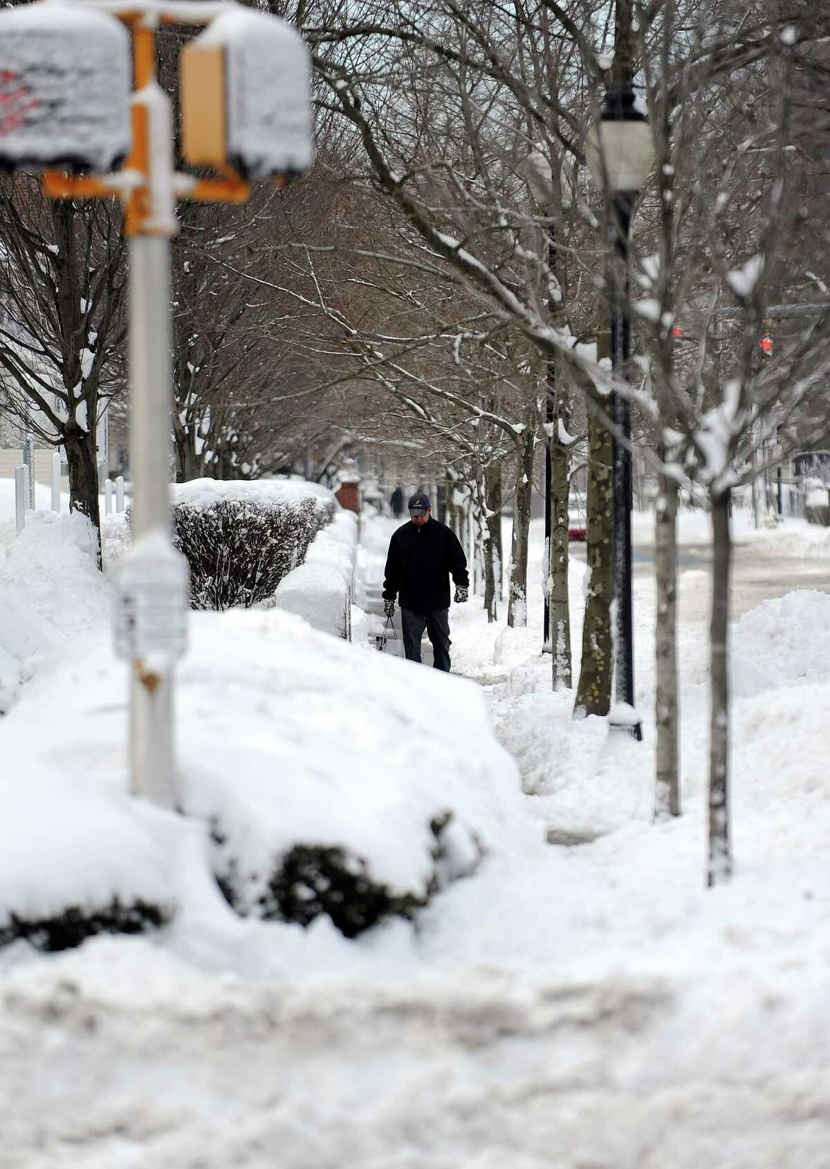A pedestrian walks down a snowy sidwalk in Stamford, Conn., on Saturday, February 9, 2013.