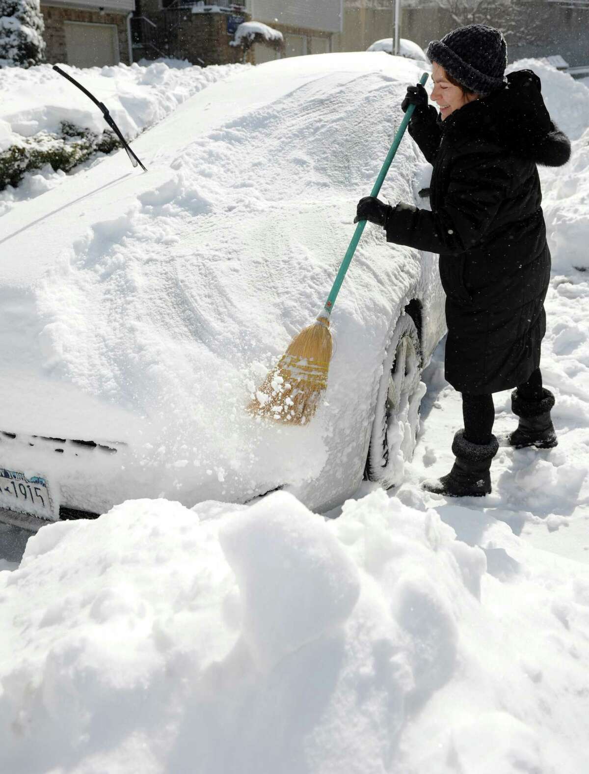 Marina Sorokin sweeps snow off her daughter's car in Stamford, Conn., on Saturday, February 9, 2013.