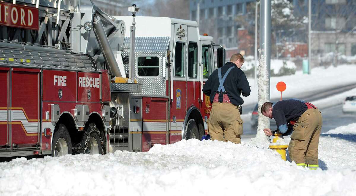 Firefighters dig out a fire hydrant buried by snow in Stamford, Conn., on Saturday, February 9, 2013.