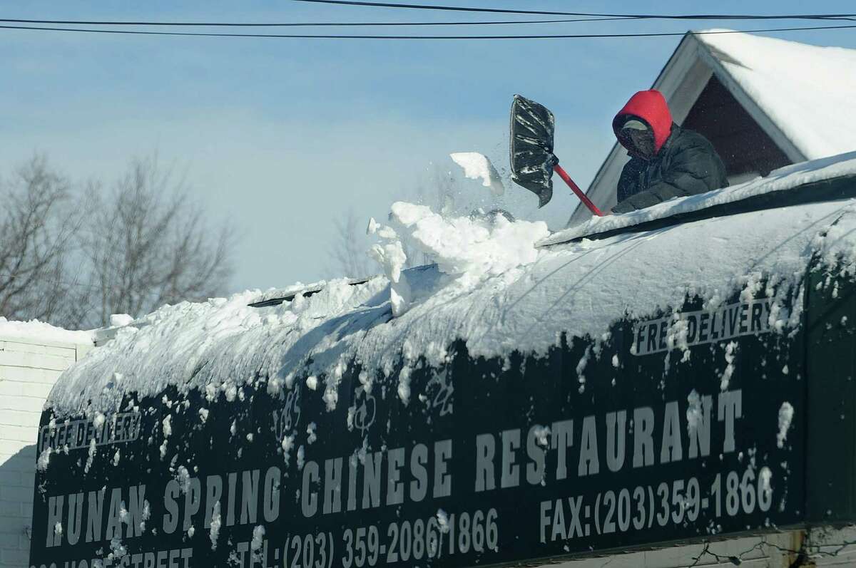 A worker clears the roof of Hunan Spring Chinese restaurant in Stamford, Conn., on Saturday, February 9, 2013.